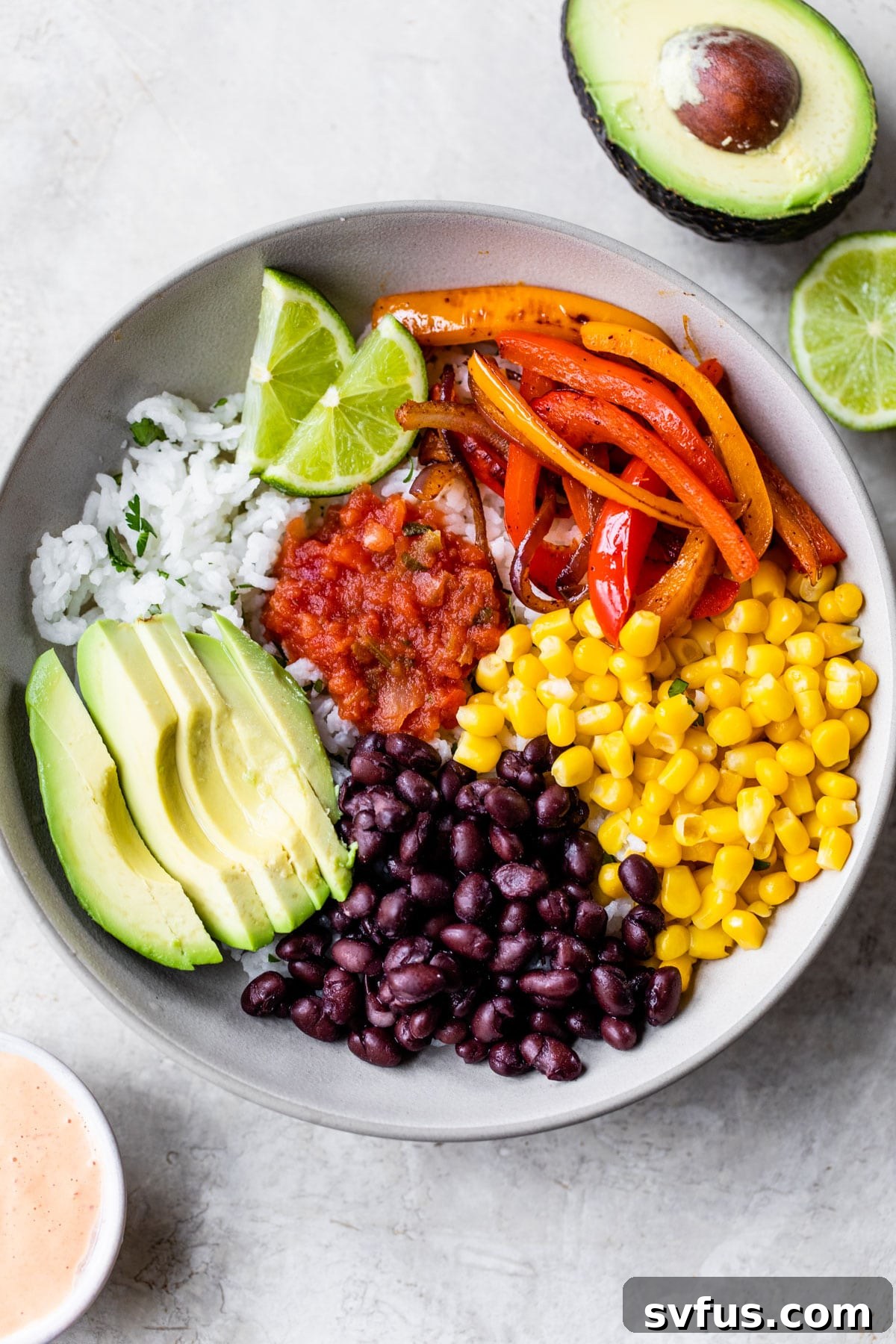 A close-up view of a vibrant vegan burrito bowl, generously filled with fluffy rice, an array of colorful sautéed vegetables, and fresh avocado slices, highlighting its wholesome ingredients.