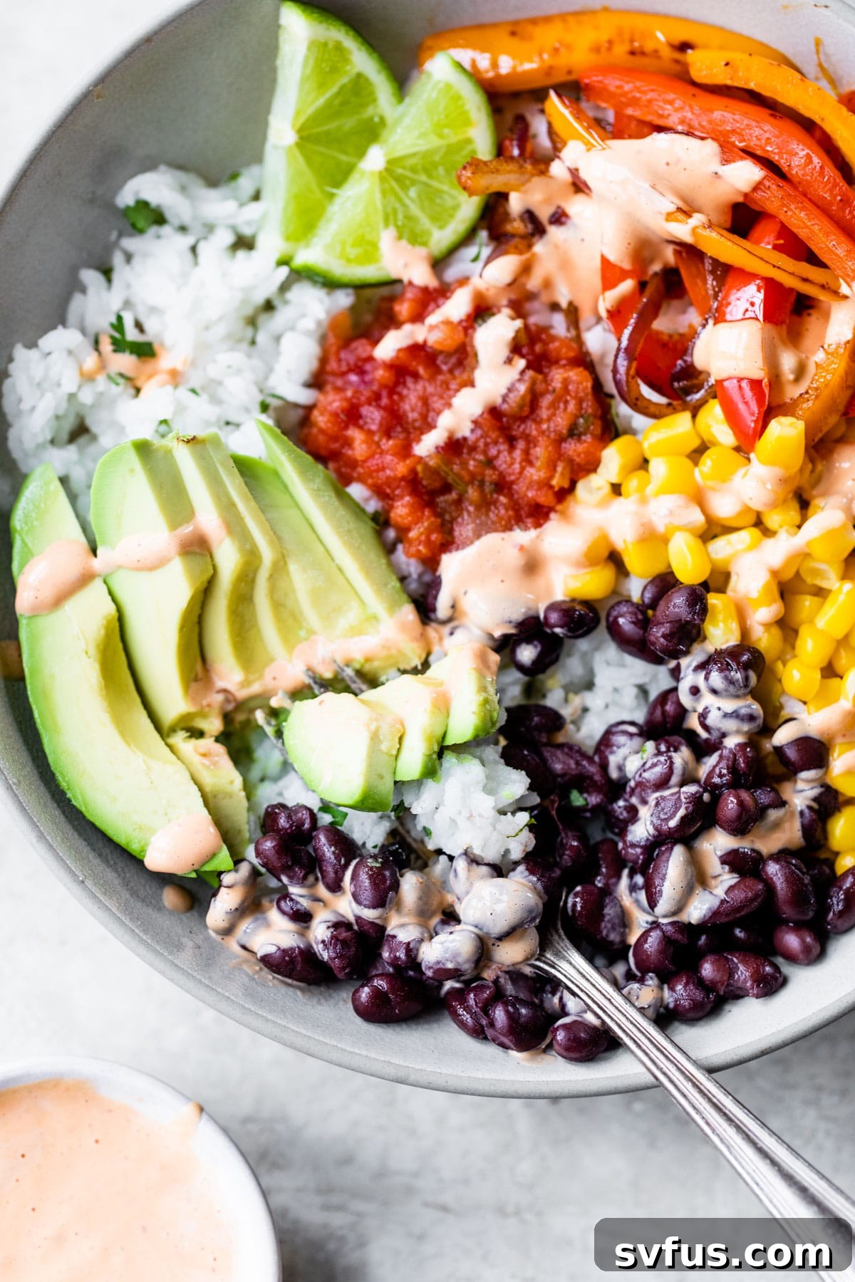 An assembled vegan burrito bowl, showcasing its colorful layers of cilantro-lime rice, black beans, corn, sautéed peppers, and fresh avocado, inviting a healthy and flavorful meal.