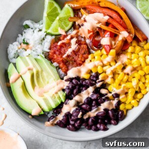 bowl of rice topped with black beans, corn, peppers, avocado, salsa, and chipotle aioli