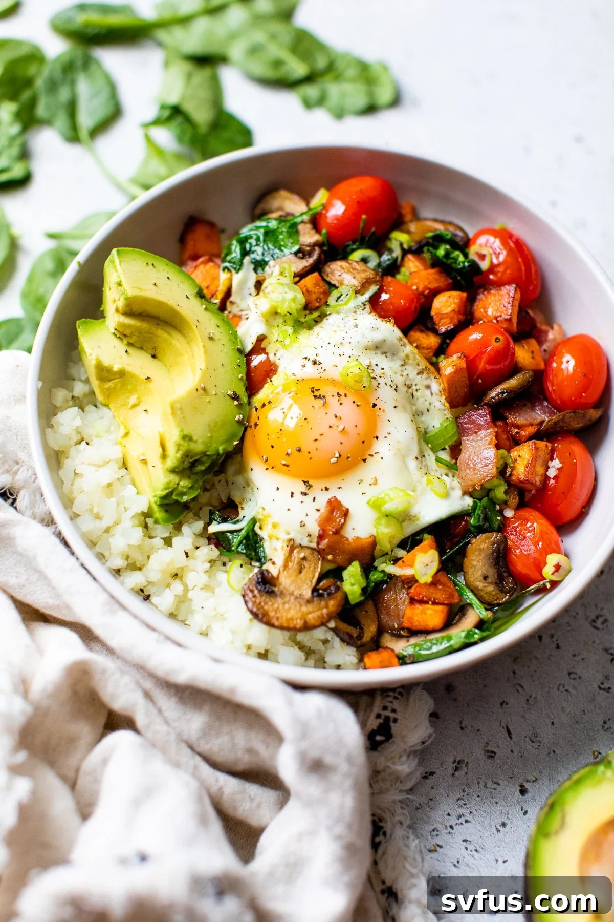 A colorful Mediterranean breakfast bowl featuring cauliflower rice, mixed vegetables, and a perfectly fried egg, offering a healthy and satisfying start to the day.