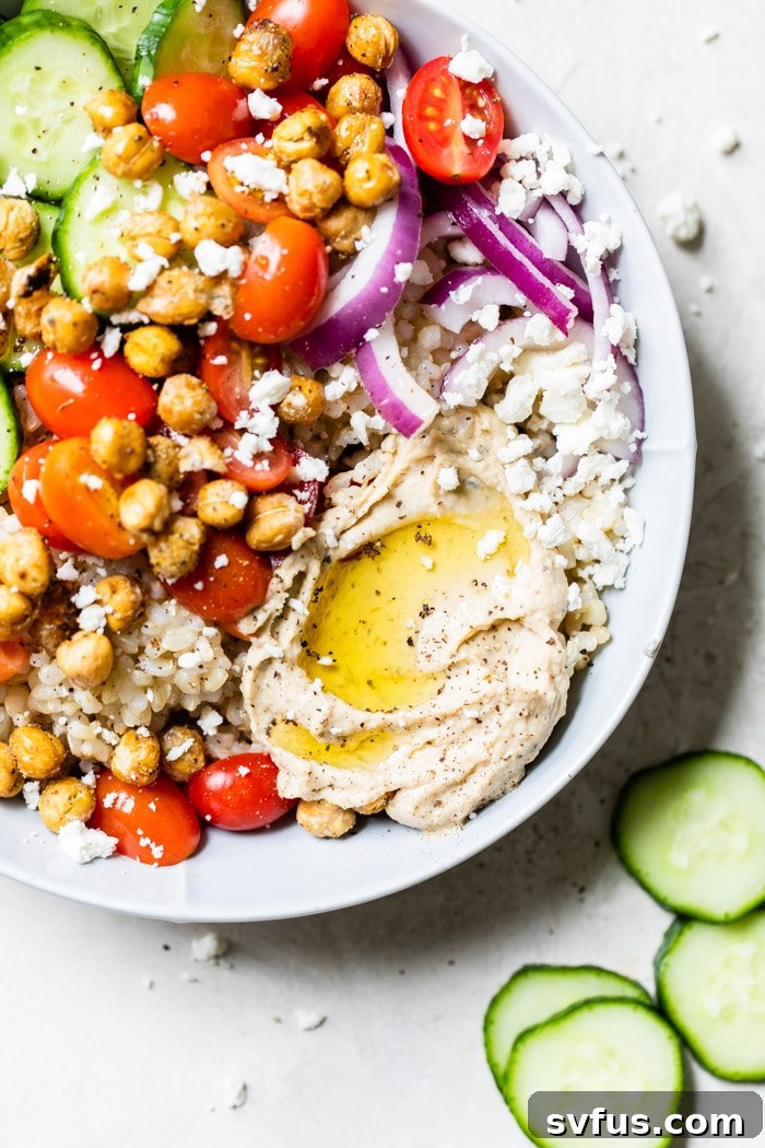 A wholesome Mediterranean Hummus Bowl filled with fluffy rice, an assortment of colorful vegetables, and creamy hummus, garnished with fresh herbs and spices.