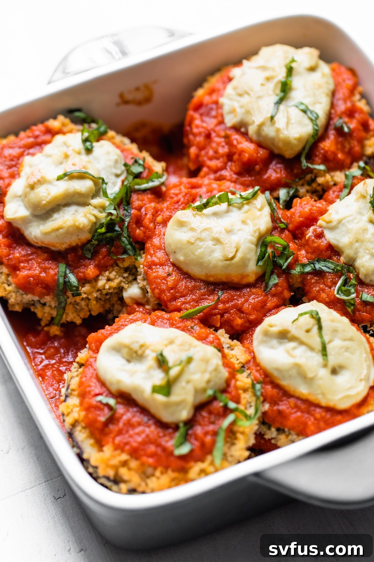 A close-up of a bubbling, cheesy Vegan Eggplant Parmesan casserole, freshly baked and ready to be served