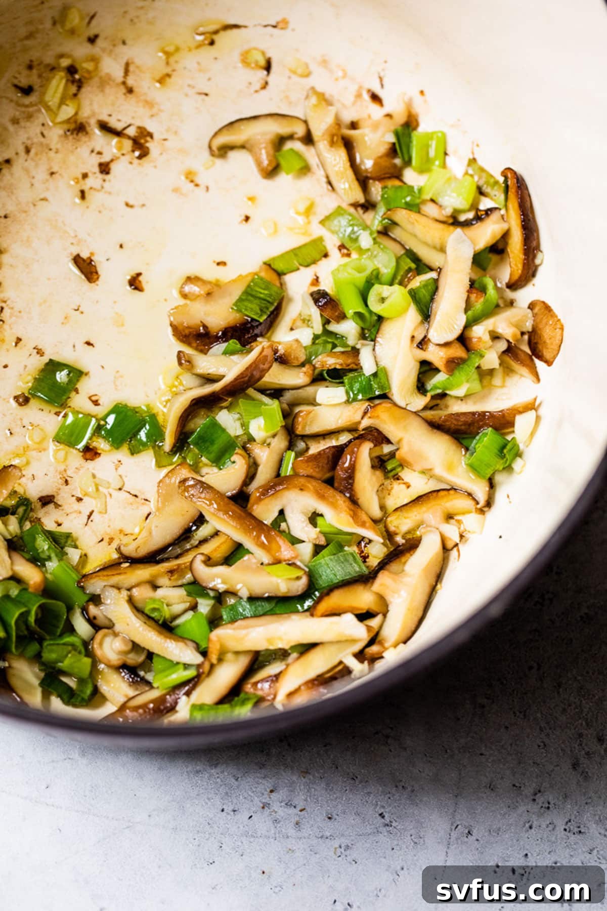 cooking mushrooms and green onions in a large pot for ramen broth.