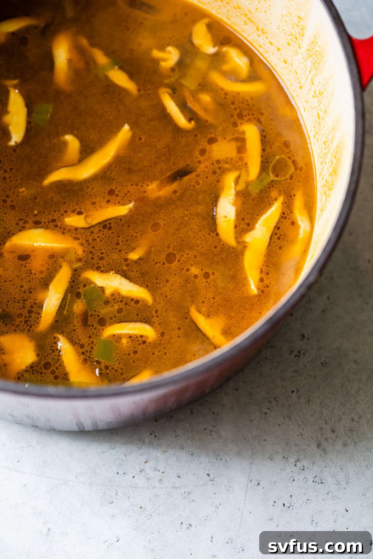 broth and cooked mushrooms simmering in a large pot, forming the base of vegan ramen.