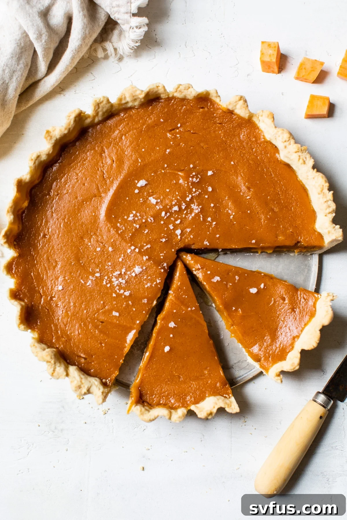 A perfectly baked Vegan Sweet Potato Pie cooling on a rustic wooden table, ready to be sliced and enjoyed.