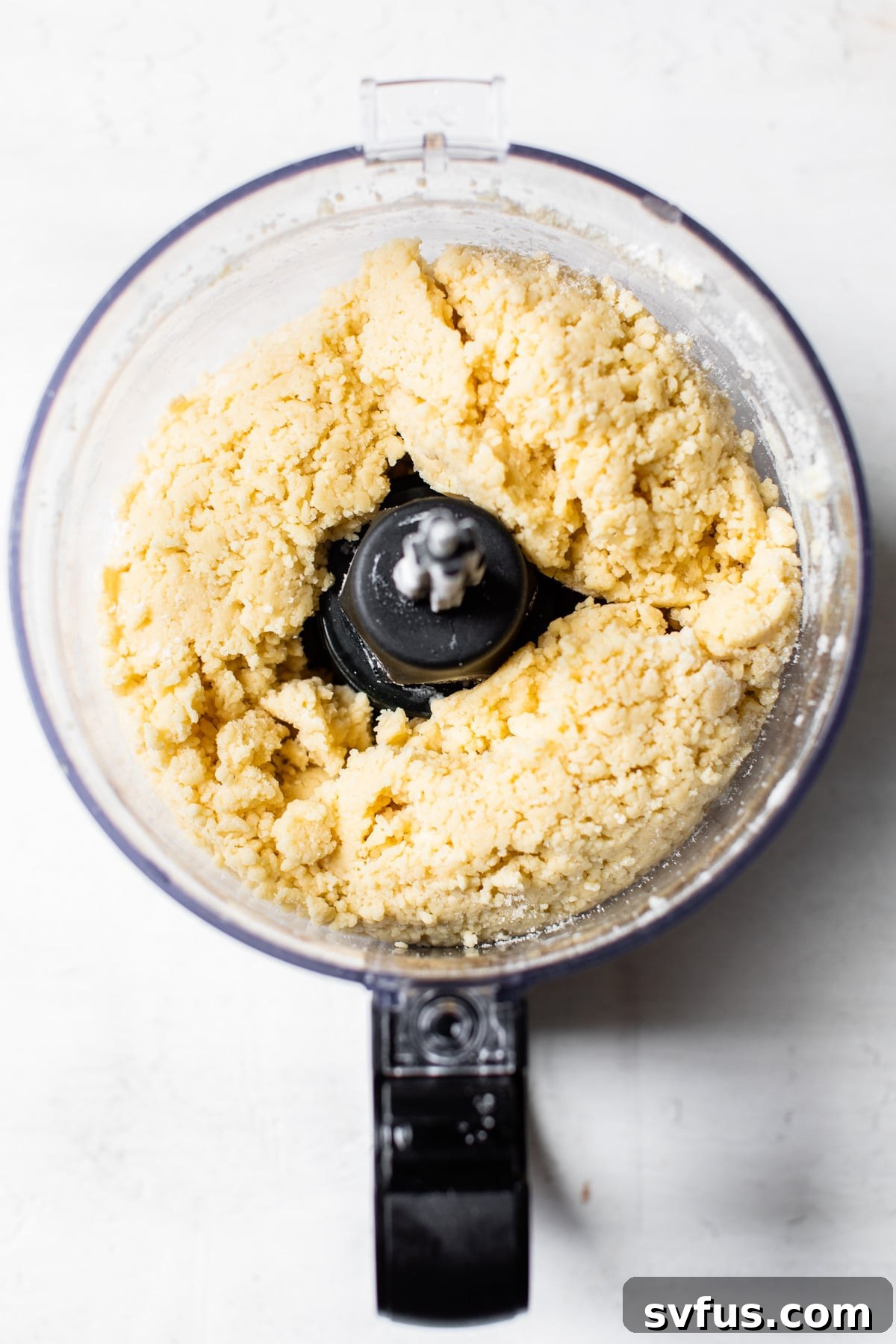 Pie dough being prepared in a food processor, illustrating the ease of making a vegan pie crust.
