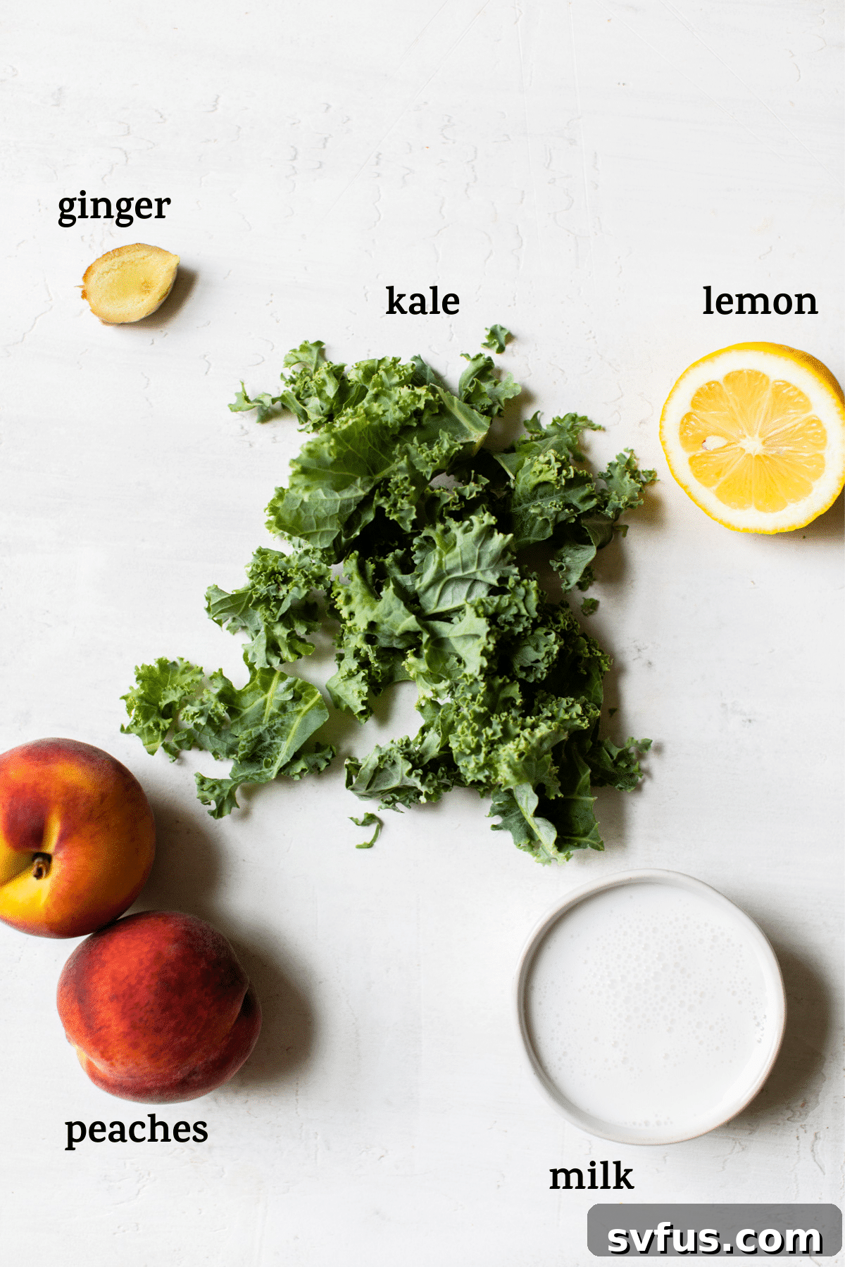Fresh ingredients for a kale smoothie: peaches, ginger, kale, lemon, and milk