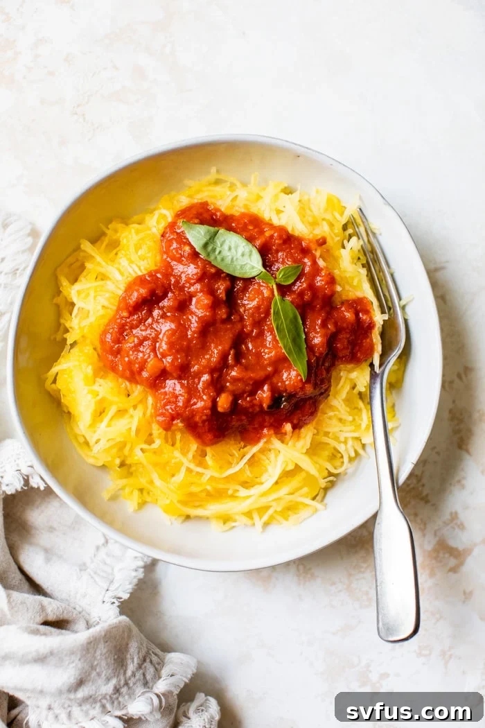 A white bowl containing spaghetti squash topped with rich marinara sauce and fresh basil leaves as a garnish. The dish looks inviting and healthy, showcasing the versatility of Instant Pot spaghetti squash.