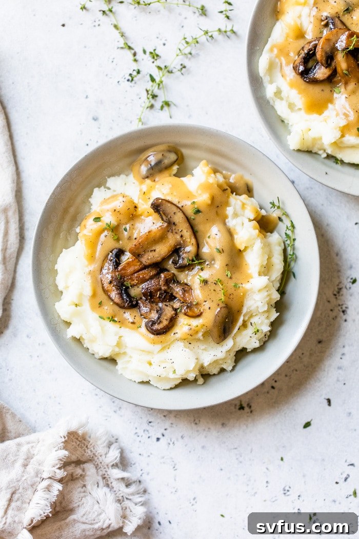 A close-up shot of the rich, creamy vegan mushroom gravy elegantly draped over a serving of mashed potatoes.