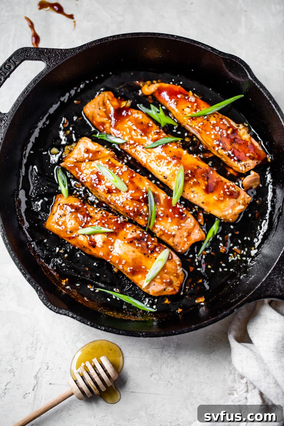 glazed salmon in a skillet topped with green onions