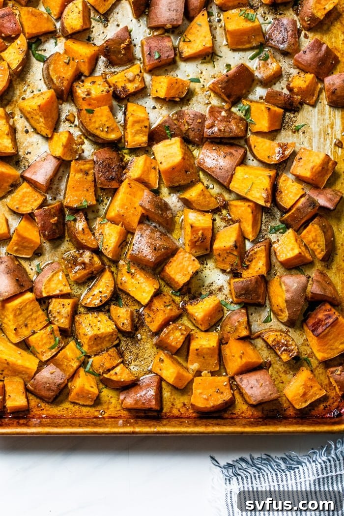 A baking sheet filled with perfectly roasted sweet potatoes, golden brown and glistening with flavor