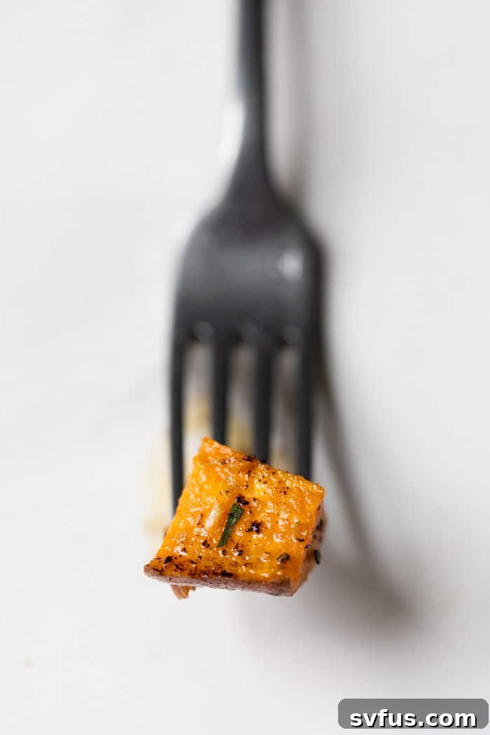 A single piece of brown butter roasted sweet potato skewered on a fork, ready to be eaten