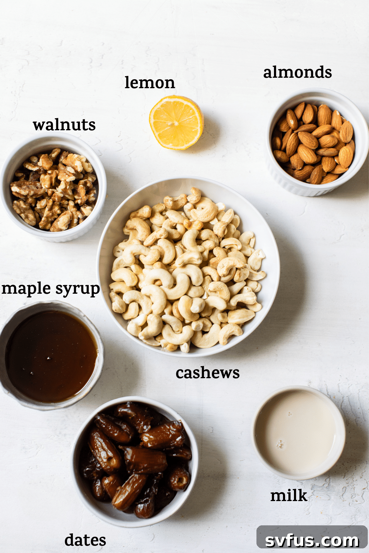 Arrangement of ingredients for no-bake vegan cheesecake, including nuts, dates, cashews, lemon, and maple syrup, set against a light background.