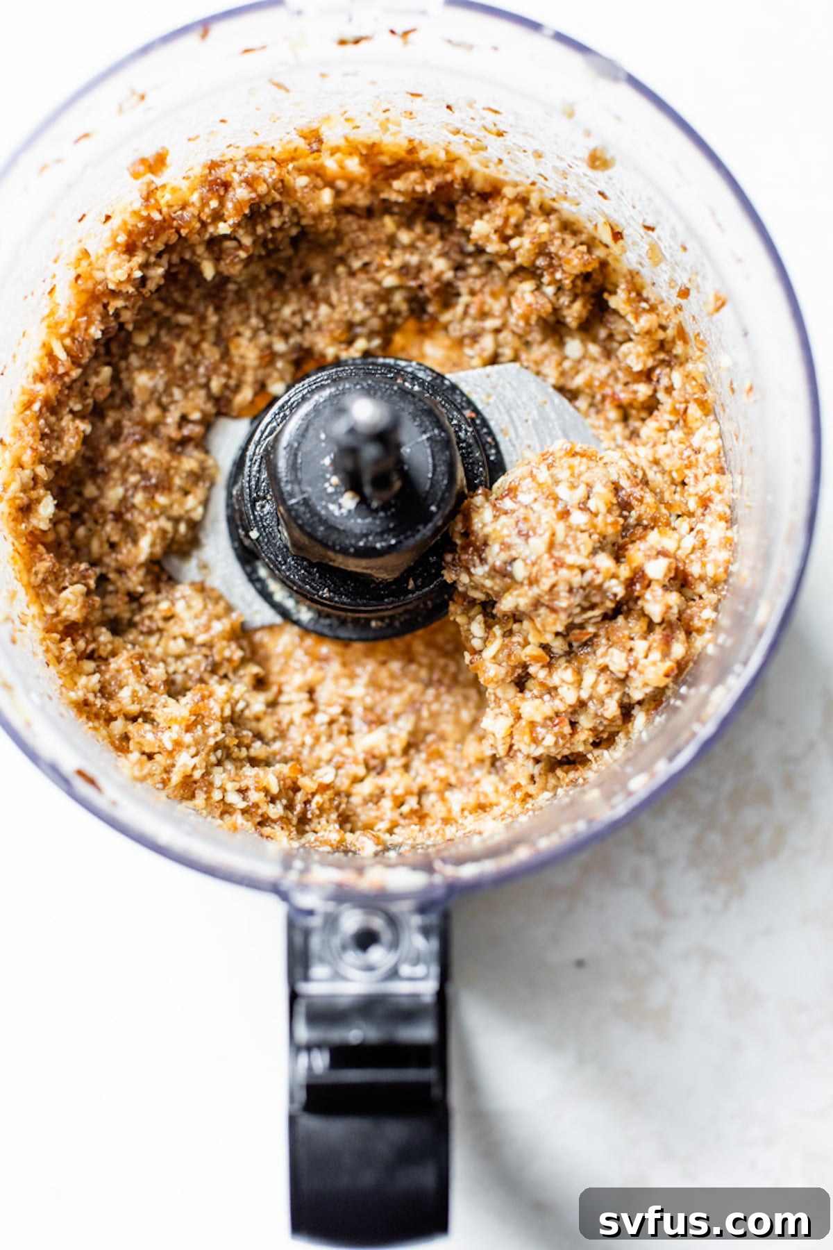 Close-up of walnuts and almonds in a food processor, ready to be blended for the cheesecake crust.