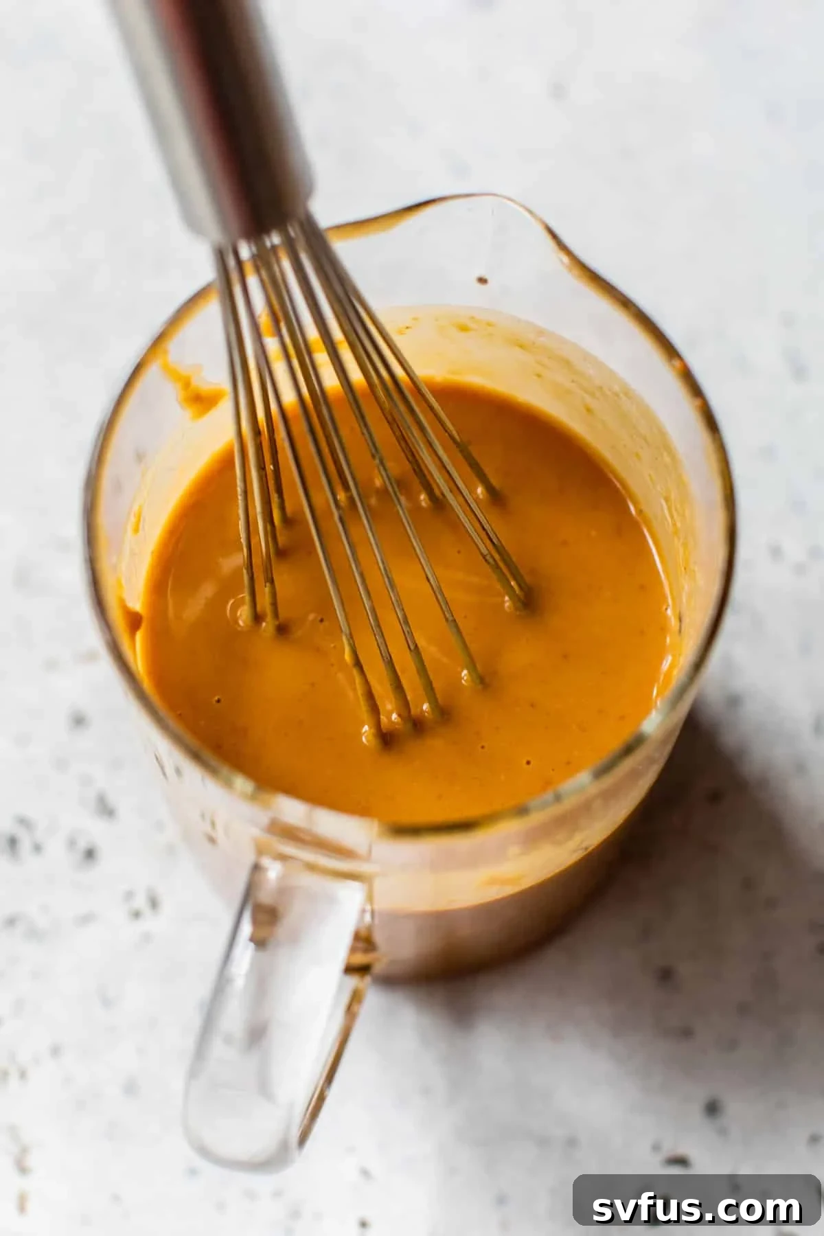 sauce ingredients in a glass measuring cup with a whisk