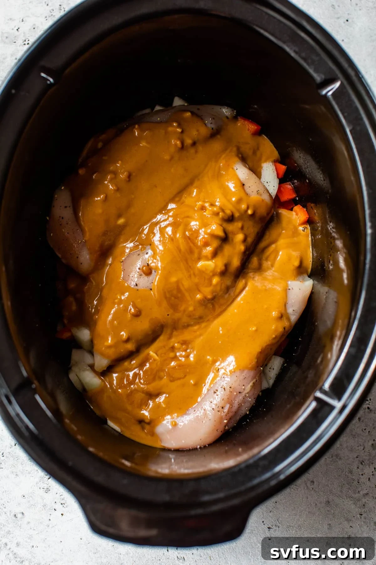 chicken breast and sauce inside of a slow cooker