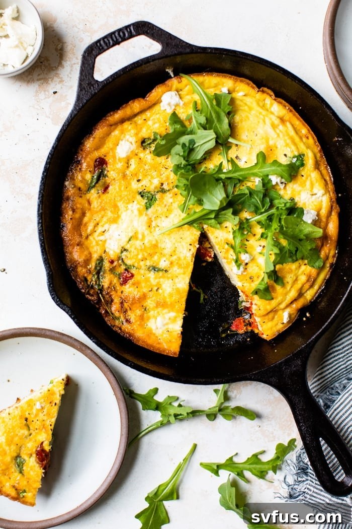 Golden-brown Sun-Dried Tomato Frittata in a rustic cast iron skillet, garnished with fresh herbs, ready to be served