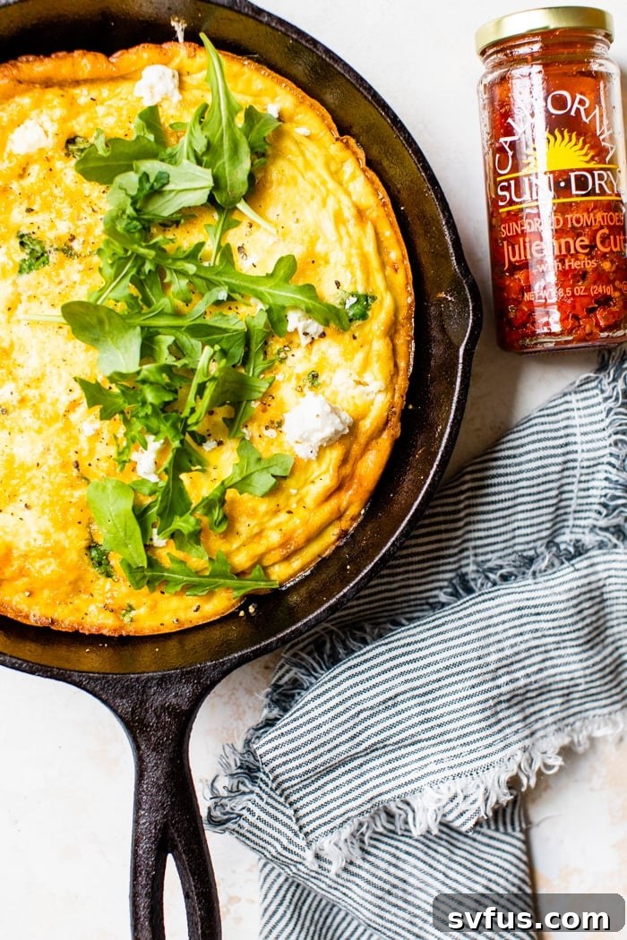 A vibrant Sun-Dried Tomato and Arugula Frittata baking in a cast iron skillet, showcasing its rich ingredients