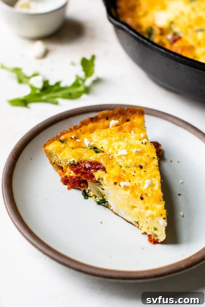 A perfectly sliced piece of Sun-Dried Tomato Frittata, showcasing its fluffy texture and rich ingredients, ready to be enjoyed