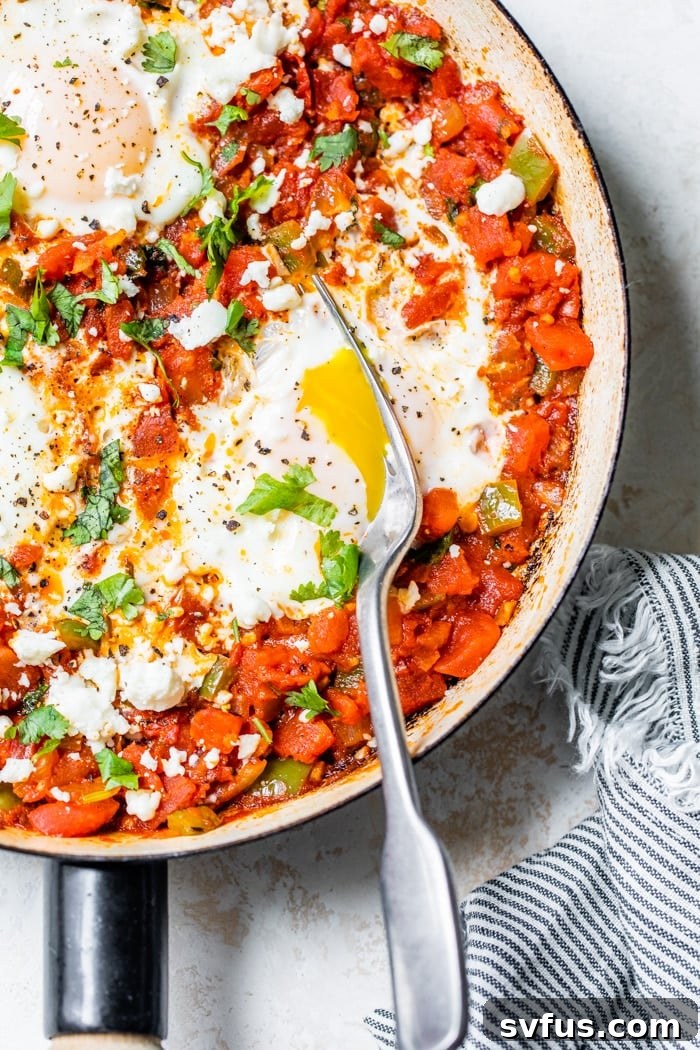 A close-up shot of a shakshuka skillet, focusing on the rich, textured tomato sauce and the perfectly cooked eggs, ready to be served.