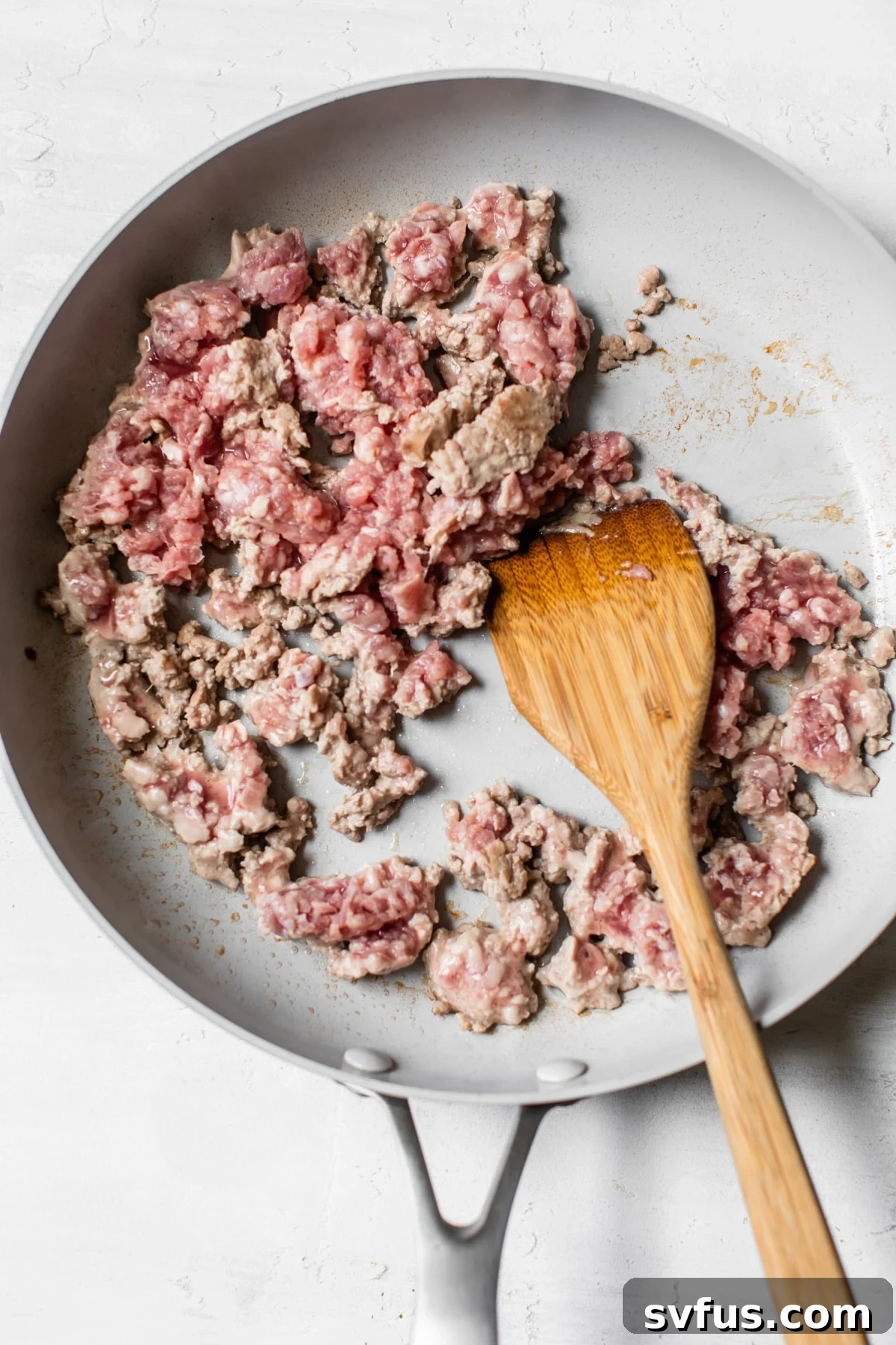 Ground pork sizzling in a non-stick skillet, browning evenly for the Banh Mi Bowl.