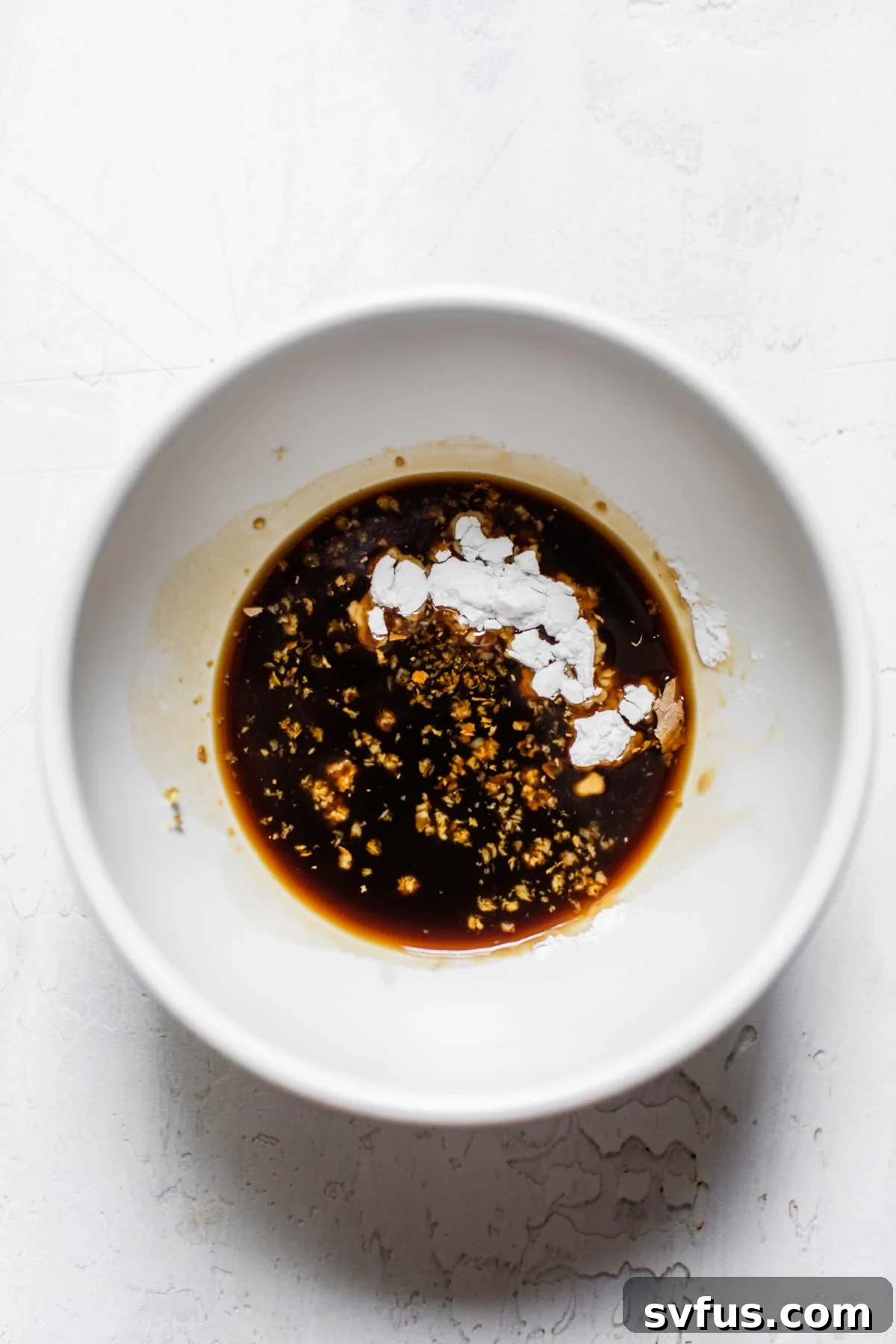 A small bowl containing the Banh Mi marinade, a mixture of coconut aminos, arrowroot, and grated ginger, ready to be added to the pork.