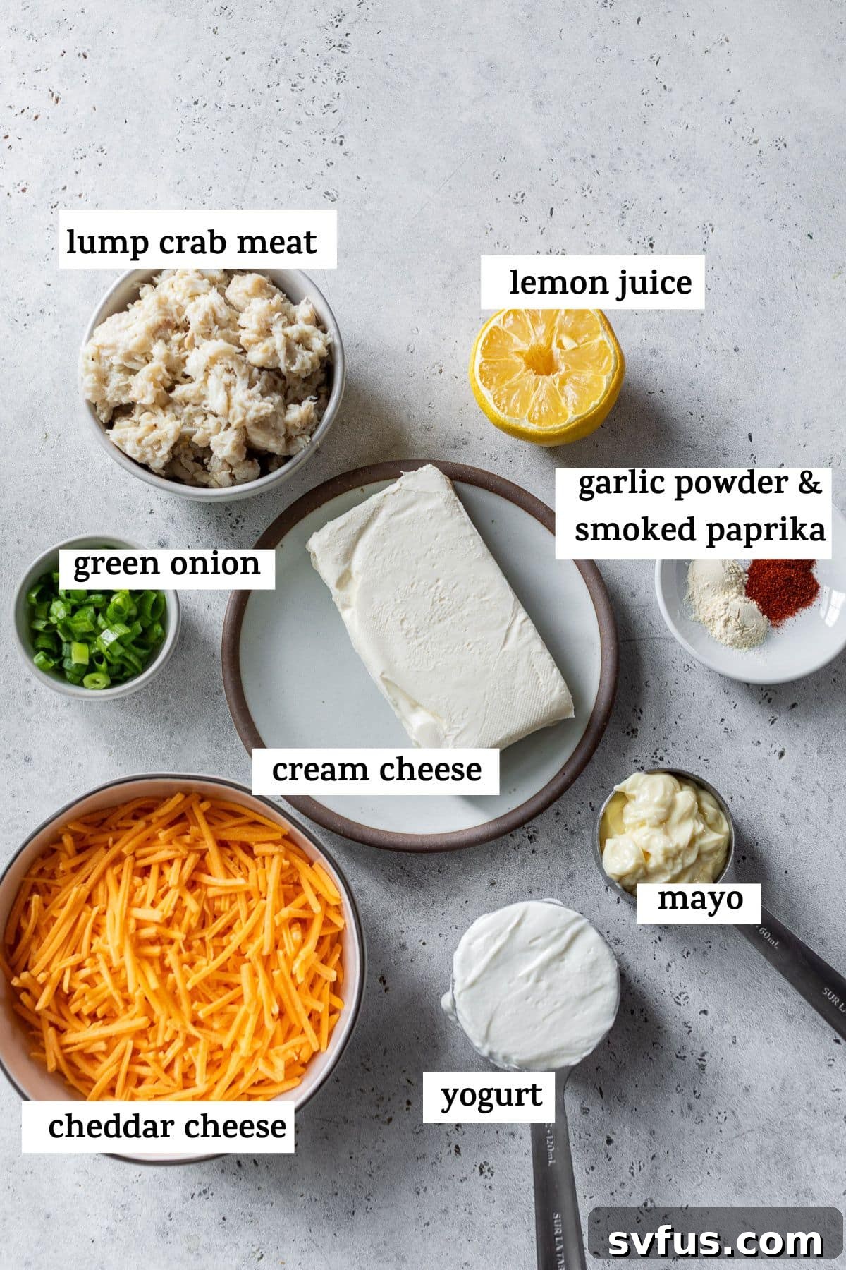 Individual bowls displaying the fresh ingredients for hot crab dip, including cream cheese, crab meat, shredded cheddar, and various seasonings.