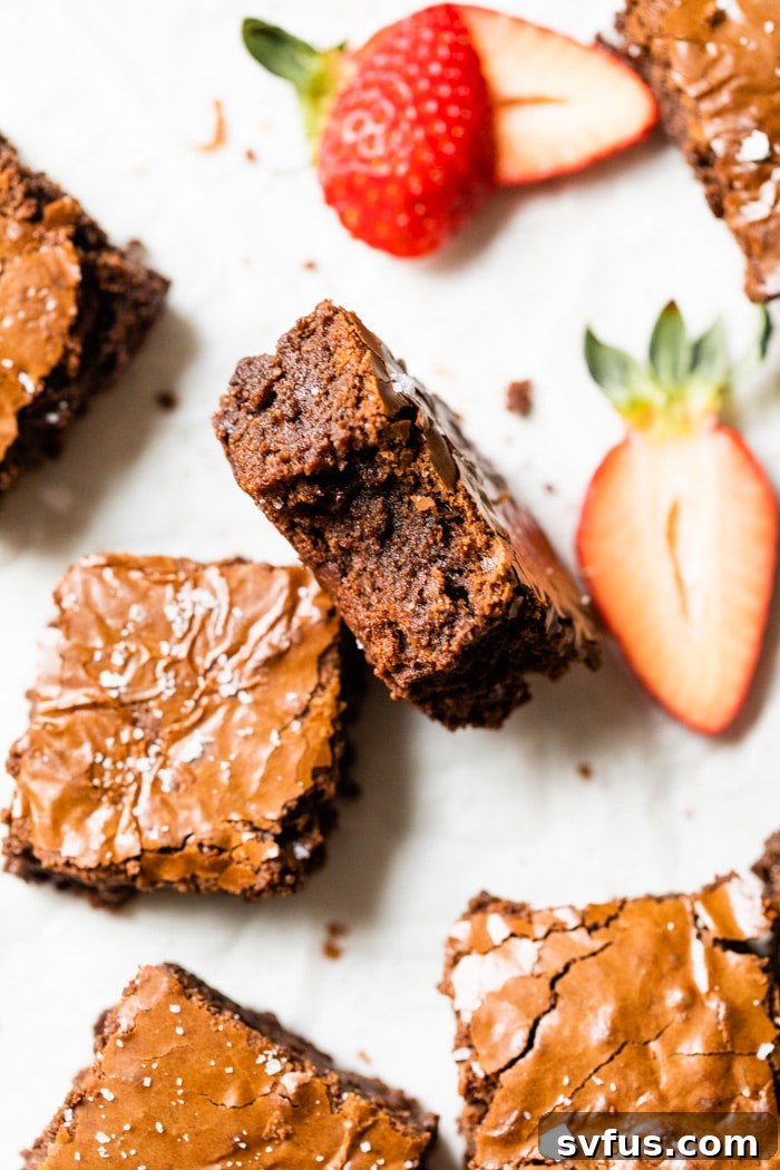 A serving of fudgy paleo brownies garnished with fresh, vibrant strawberries, highlighting their decadent appeal