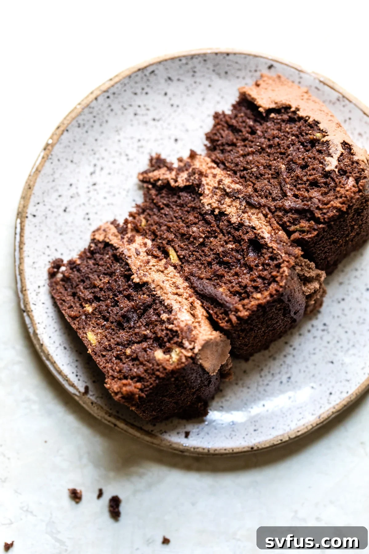 A perfectly sliced piece of rich chocolate avocado cake on a white plate, showcasing its moist texture.