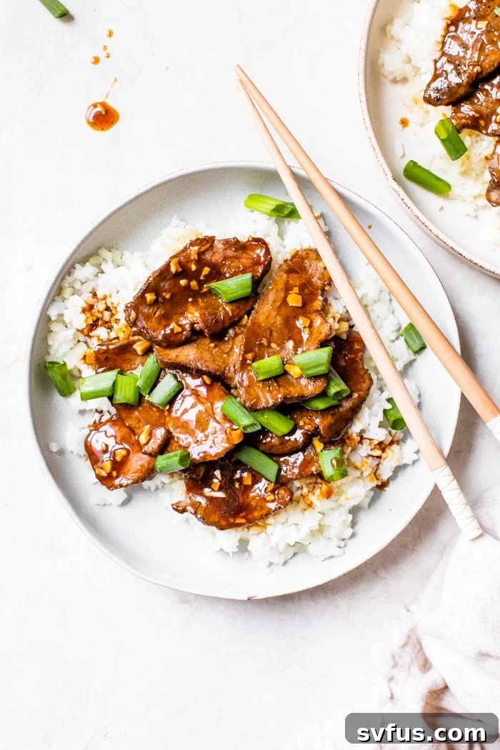 Healthy Mongolian Beef served over cauliflower rice, garnished with green onions.