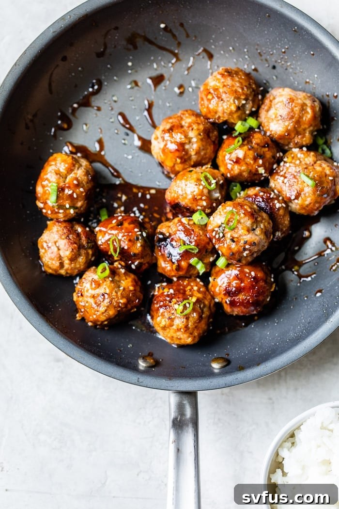 Perfectly cooked teriyaki pork meatballs in a skillet, coated in a glossy sauce.