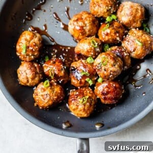 Cooked teriyaki pork meatballs in a skillet with a rich, glossy Asian sauce.