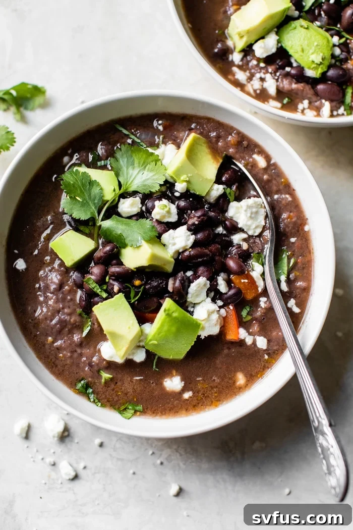 A warm bowl of perfectly seasoned, healthy, and easy-to-make black bean soup with a spoon, suitable for vegan and gluten-free diets.