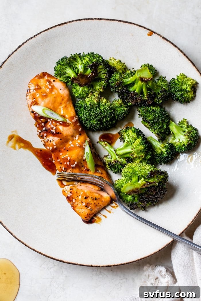 A perfectly pan-seared honey soy salmon fillet served alongside tender broccoli on a white plate, a quick and healthy 15-minute meal.