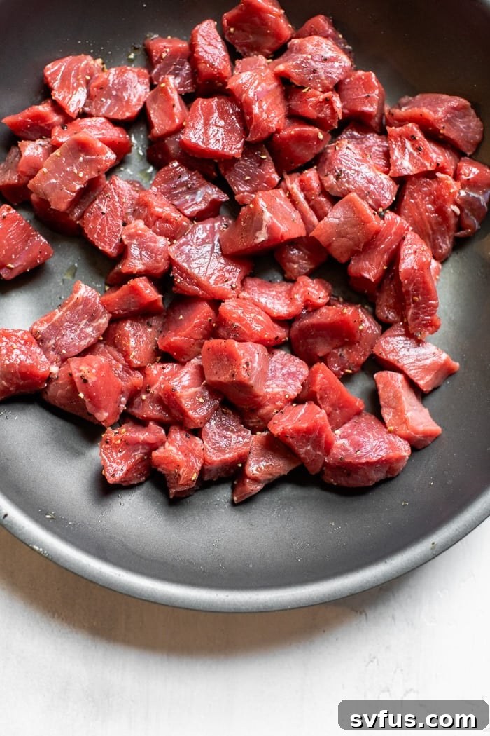 Uncooked sirloin steak cut into cubes, seasoned and ready for the skillet