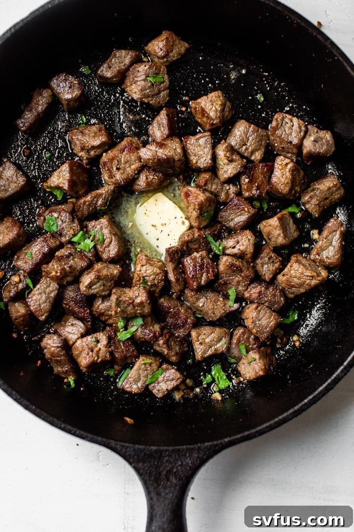Close-up of garlic butter steak bites sizzling in a cast iron skillet