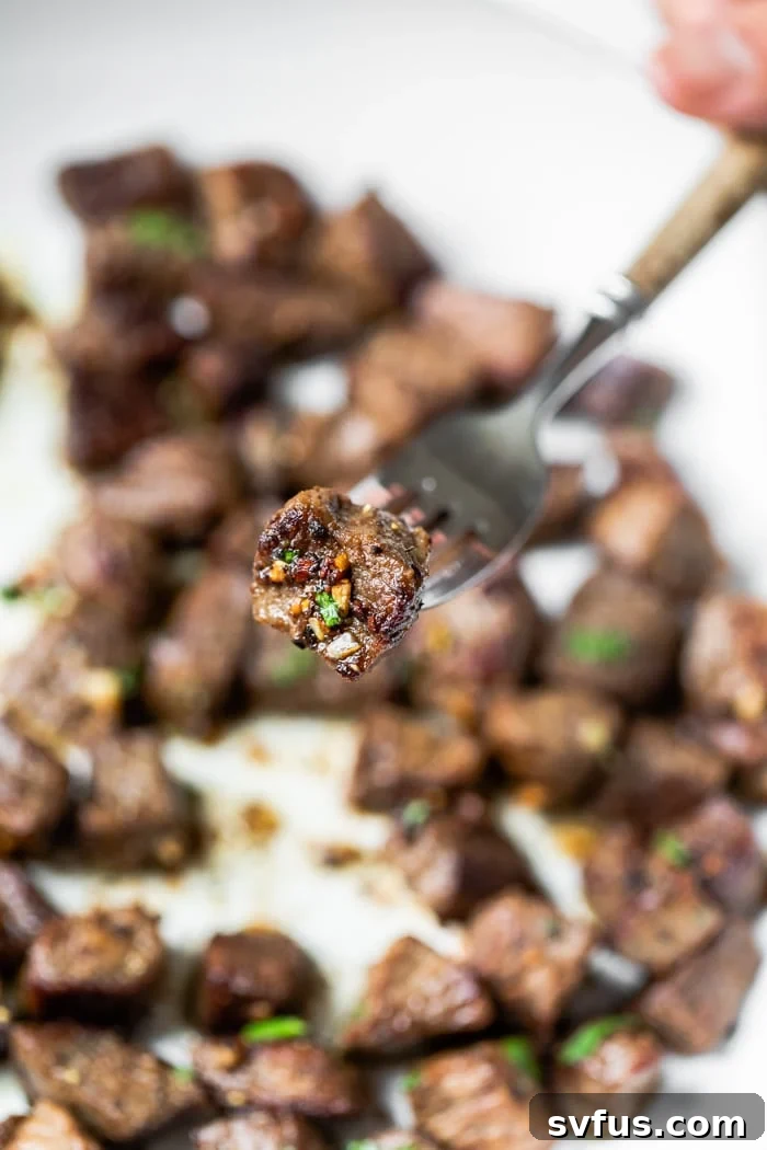 Close-up shot of a tender steak bite with minced garlic on a fork