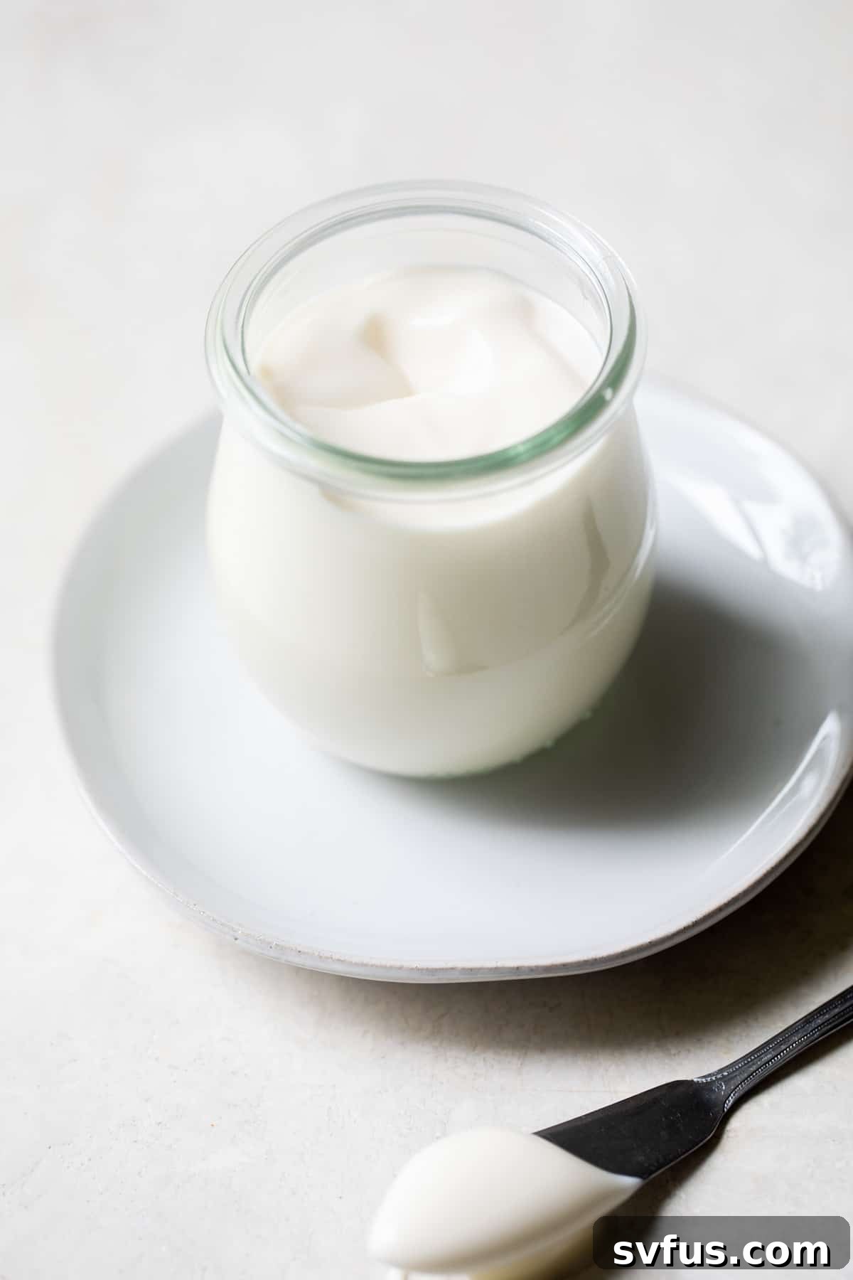A glass jar filled with creamy homemade avocado oil mayonnaise, highlighting its smooth texture and fresh appearance.