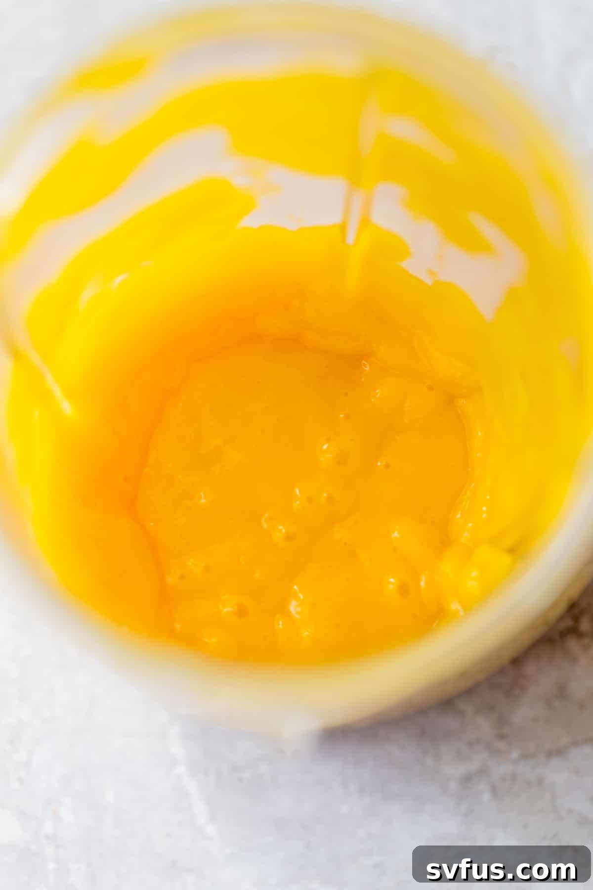 A small blender container filled with vibrant, smooth mango puree, ready to be incorporated into the mousse mixture.
