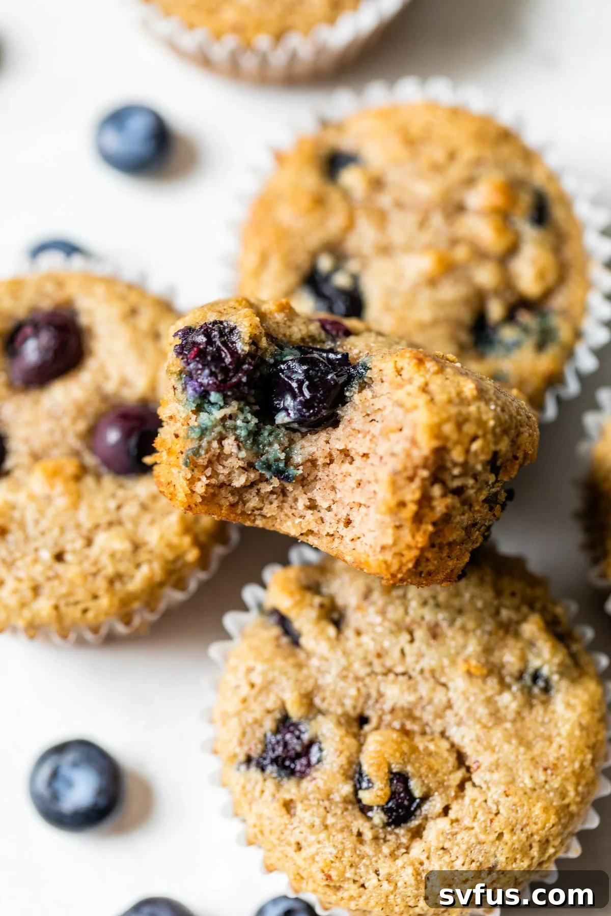 A close-up shot of a healthy almond flour blueberry muffin, showing its moist crumb and juicy blueberries, placed on a white surface