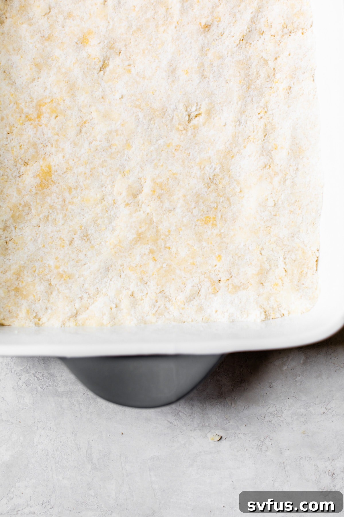 The crumb bar base pressed into an 8x8 baking dish, ready for filling