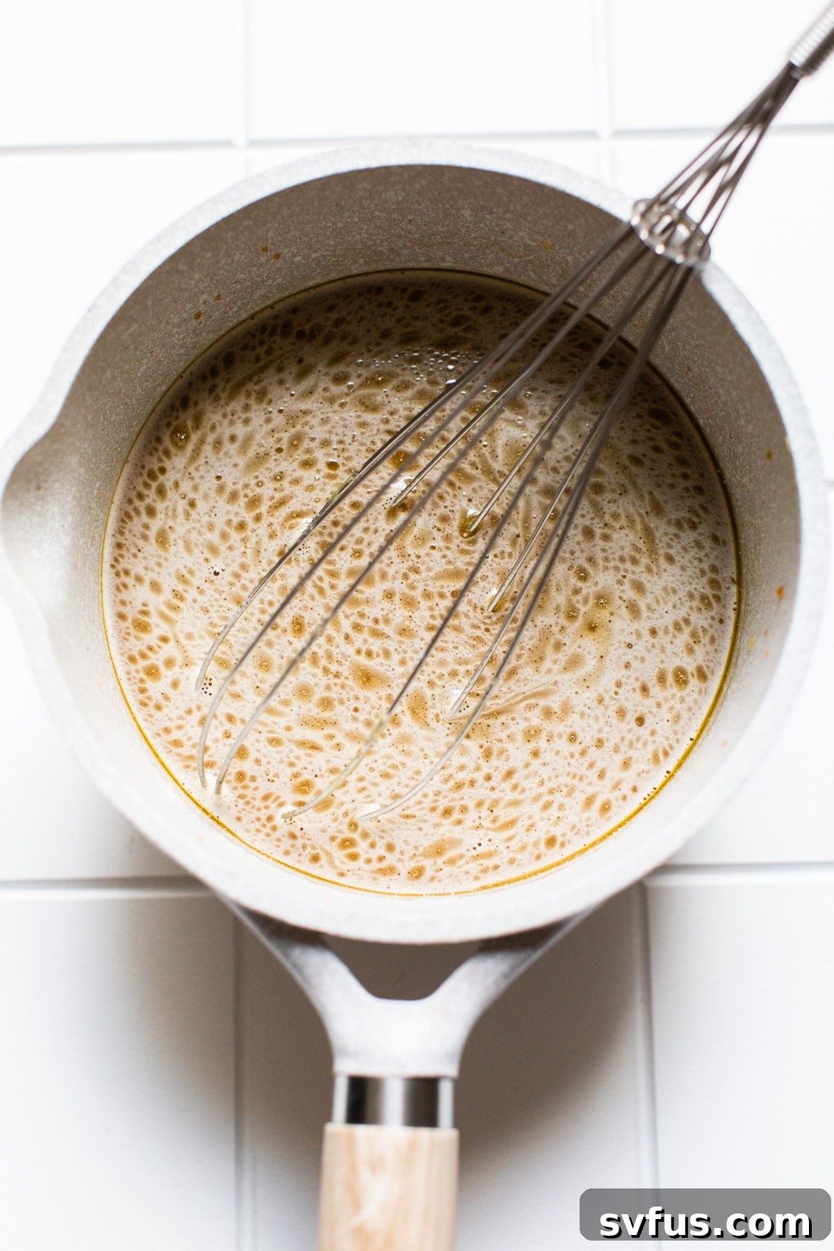 Whisking Iced Bulletproof Coffee ingredients in a saucepan for perfect emulsification