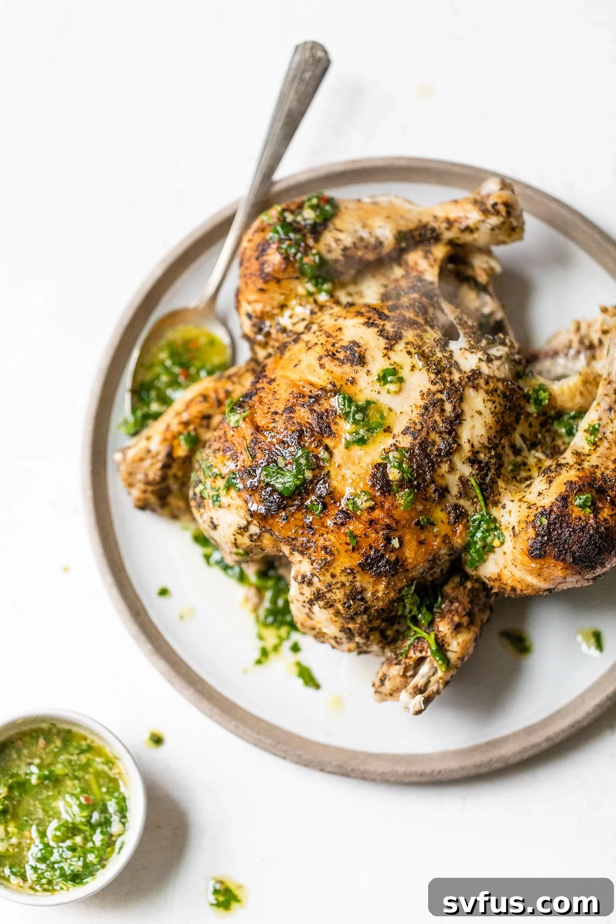 cooked rotisserie chicken on a plate drizzled with chimichurri sauce