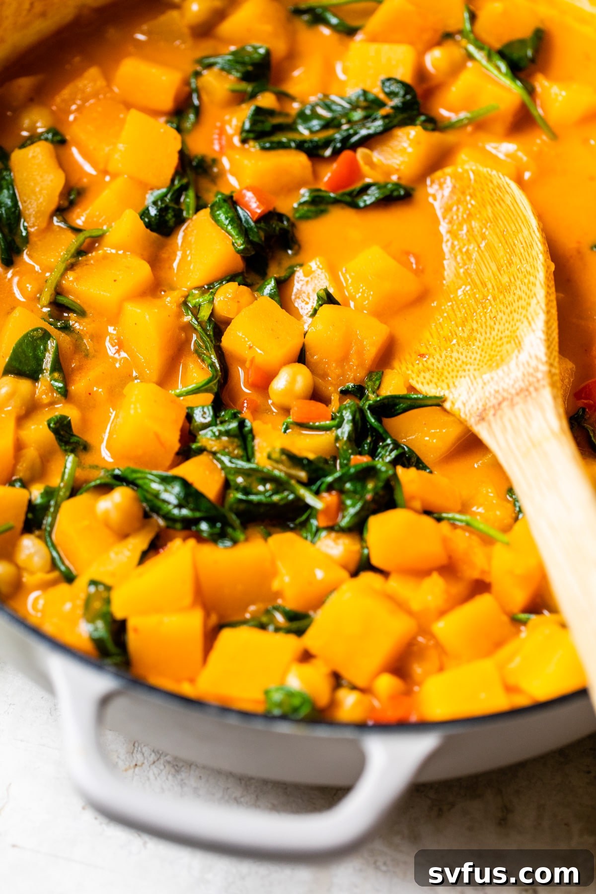 A large skillet filled with simmering butternut squash and chickpea curry, showcasing its rich, creamy texture.