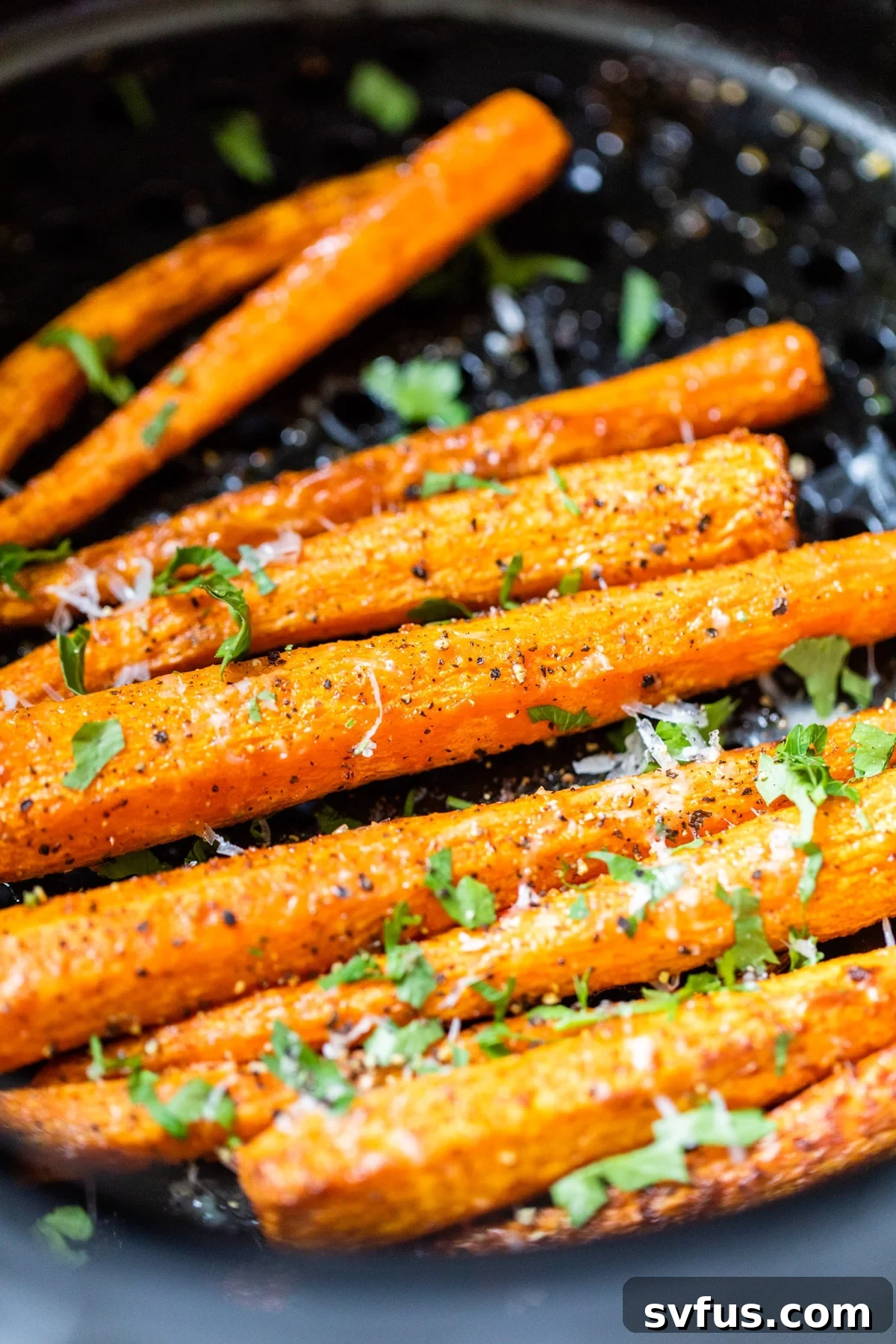 Crispy air fryer carrots topped with fresh parmesan cheese and chopped parsley, ready to serve.