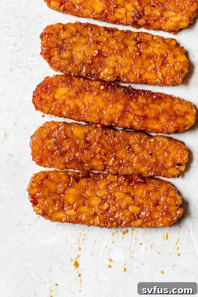 Deliciously marinated tempeh bacon strips arranged on a rustic wooden table, ready to be enjoyed.