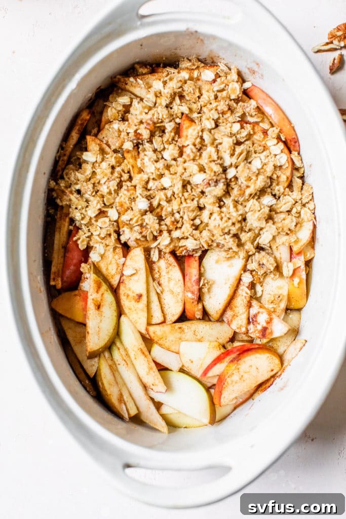 Close-up of baked apples covered with the oat and almond flour crisp topping in a baking dish.