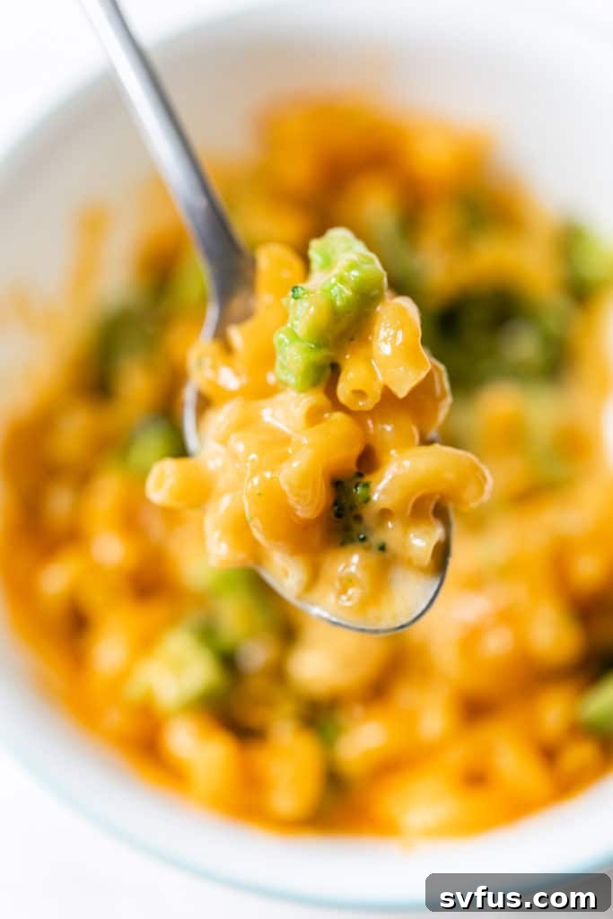 A vibrant bowl of pasta with cheese and fresh green broccoli florets, ready to be enjoyed.