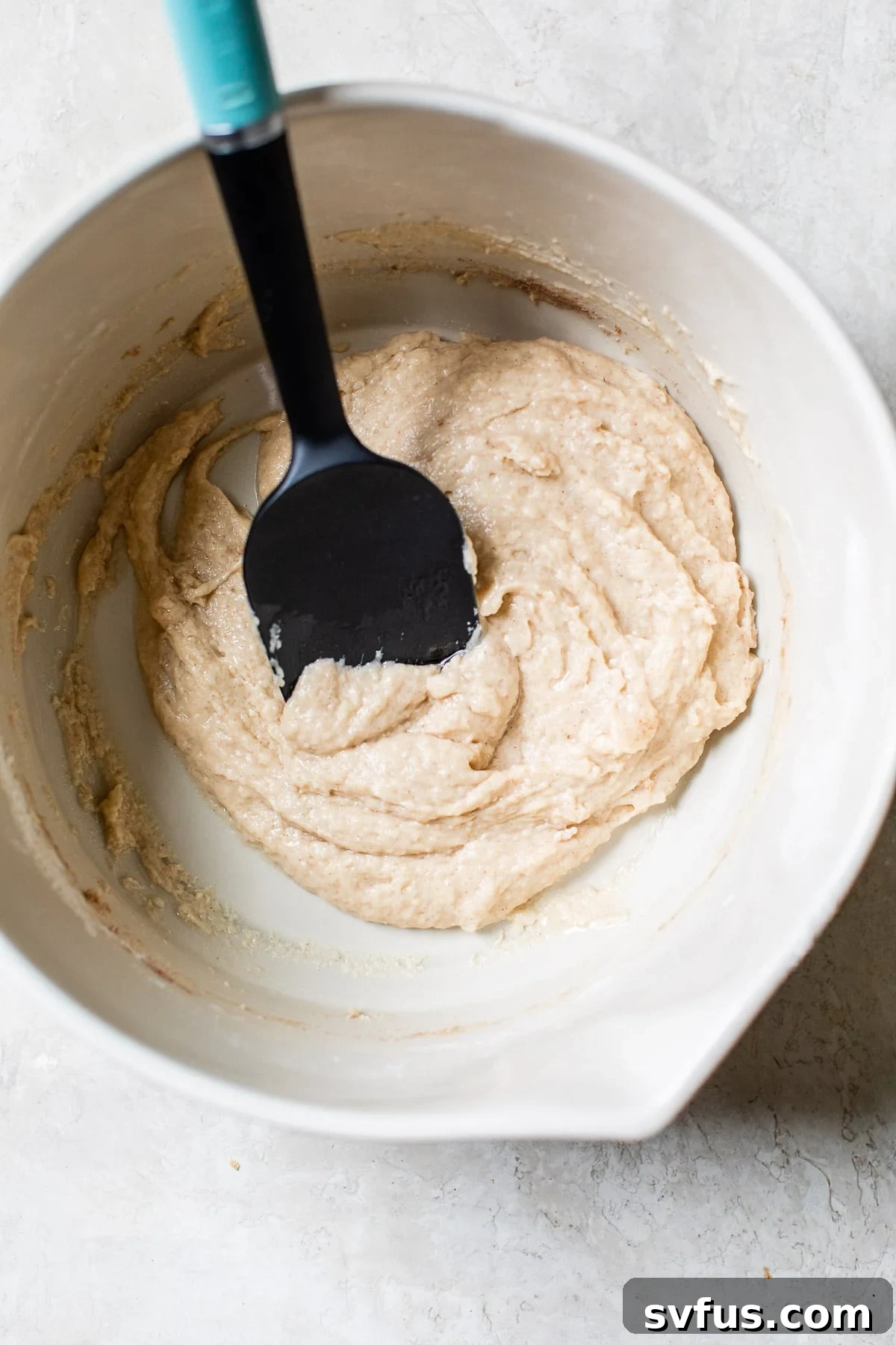 Vegan donut batter in a mixing bowl, showing its thick yet smooth consistency.