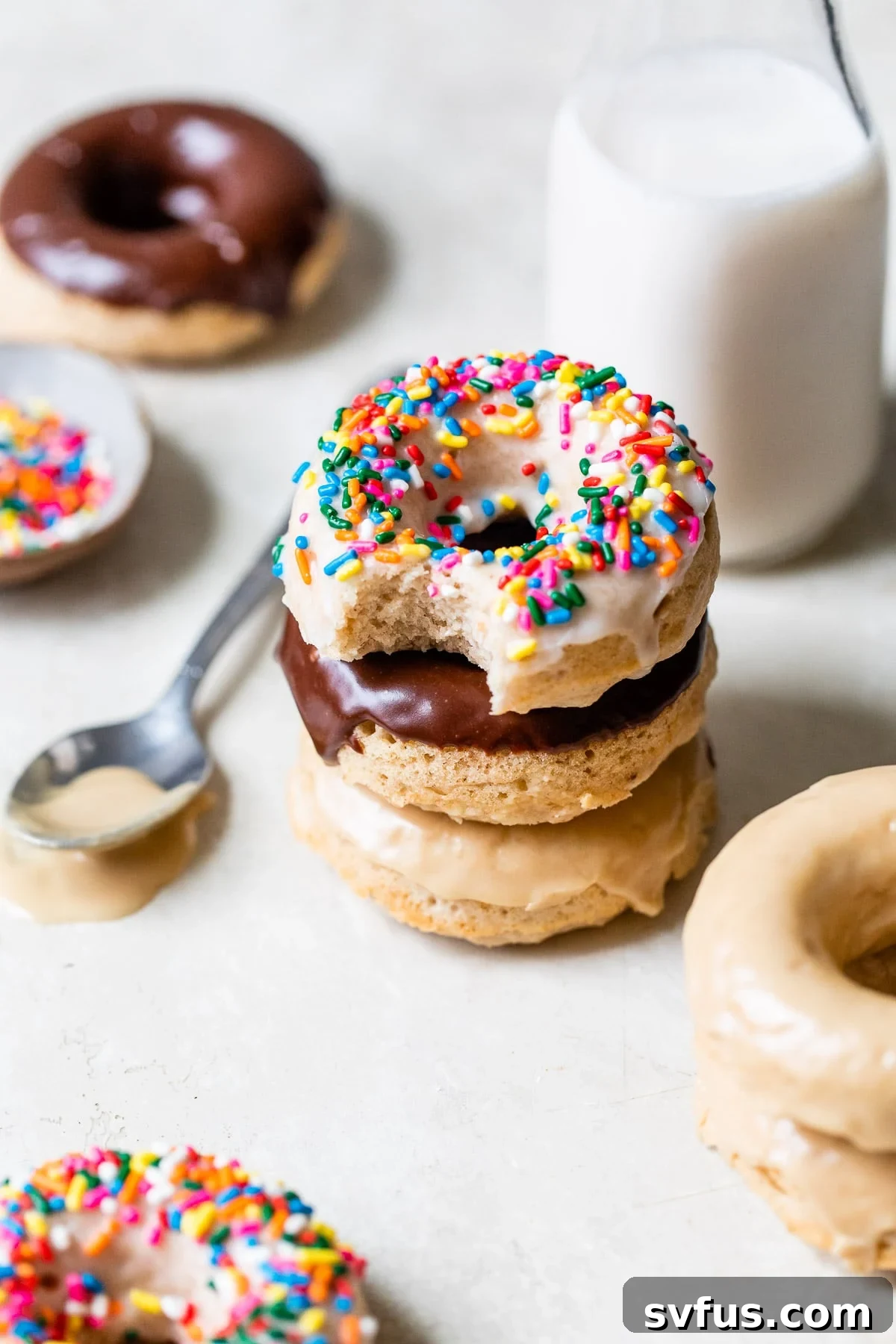 A stack of beautifully glazed vegan donuts next to a glass of dairy-free milk.